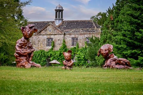 Three abstract human forms in front of mansion house